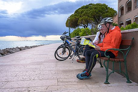 Cyclists sitting on the seafront look at the map.