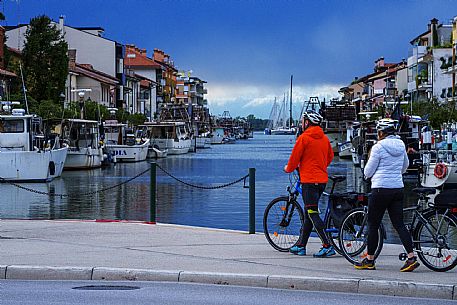 Cyclists walking on the Old Harbour in Grado.