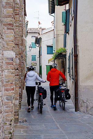 Cyclists walking in Grado's old town.