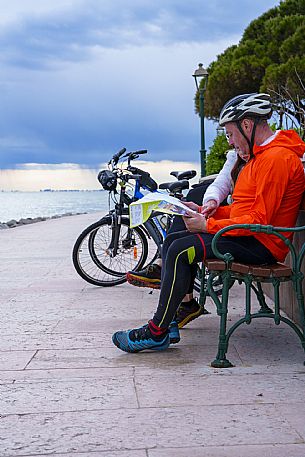 Cyclists sitting on the seafront look at the map.