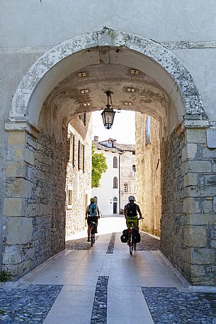 Cyclists near western tower in Spilimbergo.