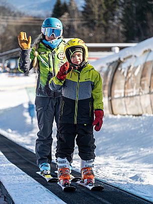 Teacher young woman and child learning alpine skiing in a school camp in Tarvisio.