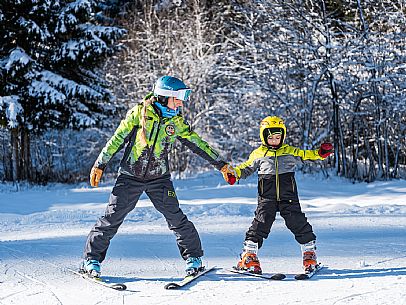 Teacher young woman and child learning alpine skiing in a school camp in Tarvisio.