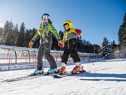 Teacher young woman and child learning alpine skiing in a school camp in Tarvisio.