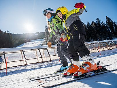 Teacher young woman and child learning alpine skiing in a school camp in Tarvisio.