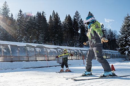 Teacher young woman and child learning alpine skiing in a school camp in Tarvisio.