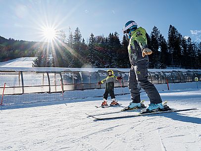 Teacher young woman and child learning alpine skiing in a school camp in Tarvisio.