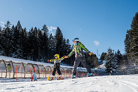 Teacher young woman and child learning alpine skiing in a school camp in Tarvisio.