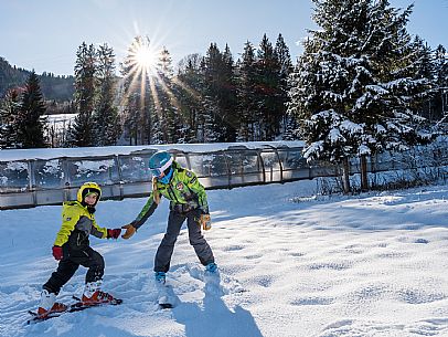 Teacher young woman and child learning alpine skiing in a school camp in Tarvisio.