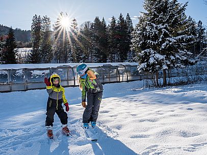 Teacher young woman and child learning alpine skiing in a school camp in Tarvisio.