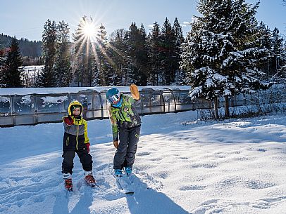 Teacher young woman and child learning alpine skiing in a school camp in Tarvisio.