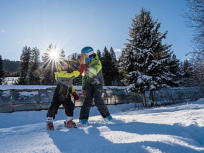 Teacher young woman and child learning alpine skiing in a school camp in Tarvisio.