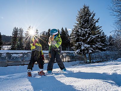 Teacher young woman and child learning alpine skiing in a school camp in Tarvisio.