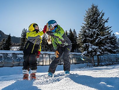 Teacher young woman and child learning alpine skiing in a school camp in Tarvisio.