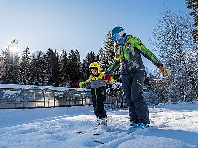 Teacher young woman and child learning alpine skiing in a school camp in Tarvisio.