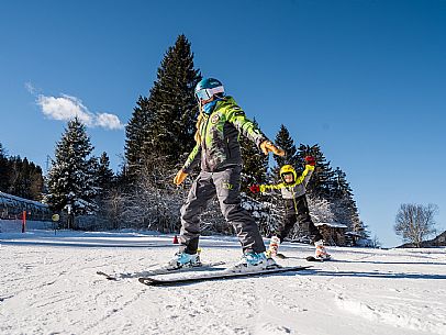 Teacher young woman and child learning alpine skiing in a school camp in Tarvisio.