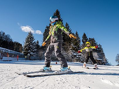 Teacher young woman and child learning alpine skiing in a school camp in Tarvisio.