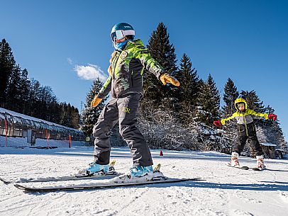 Teacher young woman and child learning alpine skiing in a school camp in Tarvisio.