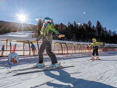 Teacher young woman and child learning alpine skiing in a school camp in Tarvisio.