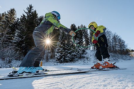 Teacher young woman and child learning alpine skiing in a school camp in Tarvisio.