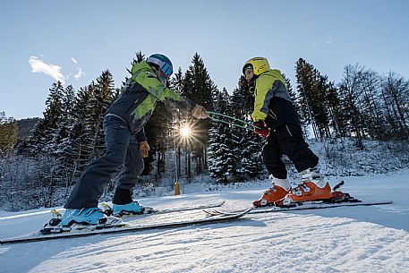 Teacher young woman and child learning alpine skiing in a school camp in Tarvisio.