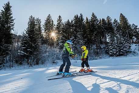 Teacher young woman and child learning alpine skiing in a school camp in Tarvisio.