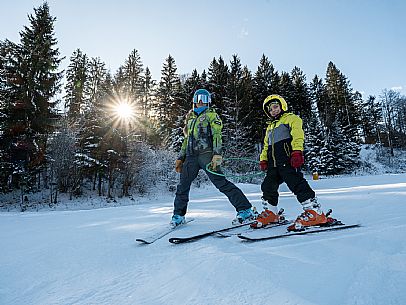 Teacher young woman and child learning alpine skiing in a school camp in Tarvisio.