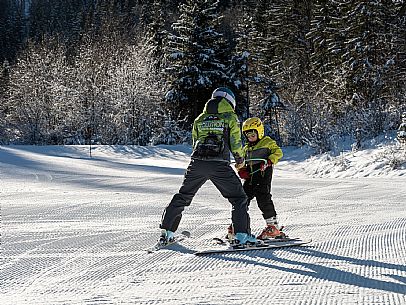 Teacher young woman and child learning alpine skiing in a school camp in Tarvisio.