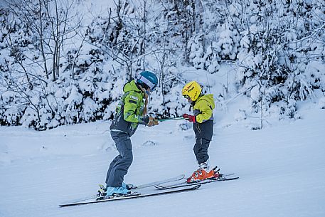 Teacher young woman and child learning alpine skiing in a school camp in Tarvisio.