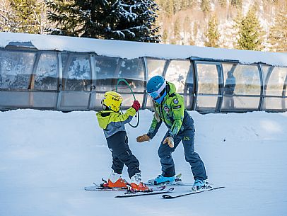 Teacher young woman and child learning alpine skiing in a school camp in Tarvisio.