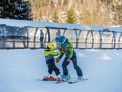 Teacher young woman and child learning alpine skiing in a school camp in Tarvisio.