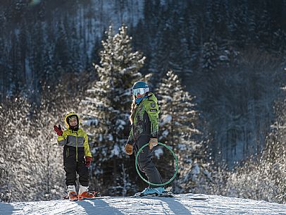 Teacher young woman and child learning alpine skiing in a school camp in Tarvisio.