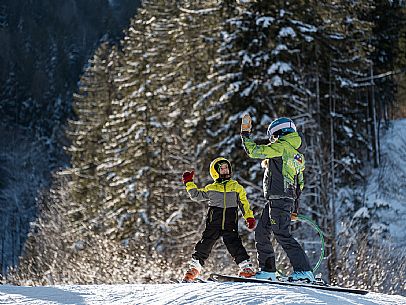 Teacher young woman and child learning alpine skiing in a school camp in Tarvisio.