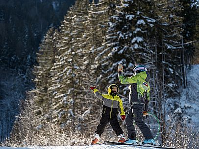 Teacher young woman and child learning alpine skiing in a school camp in Tarvisio.