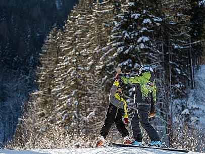 Teacher young woman and child learning alpine skiing in a school camp in Tarvisio.