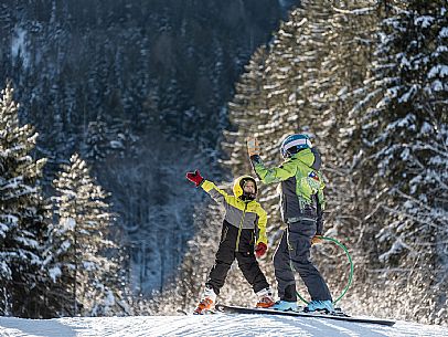 Teacher young woman and child learning alpine skiing in a school camp in Tarvisio.