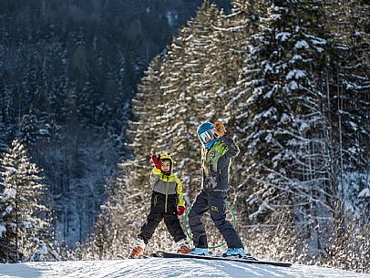 Teacher young woman and child learning alpine skiing in a school camp in Tarvisio.