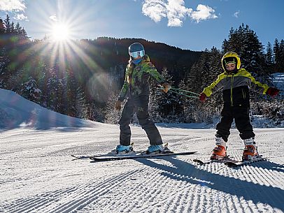 Teacher young woman and child learning alpine skiing in a school camp in Tarvisio.