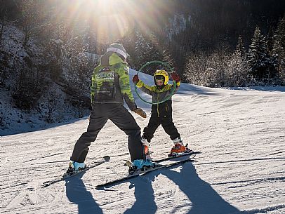 Teacher young woman and child learning alpine skiing in a school camp in Tarvisio.