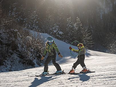 Teacher young woman and child learning alpine skiing in a school camp in Tarvisio.