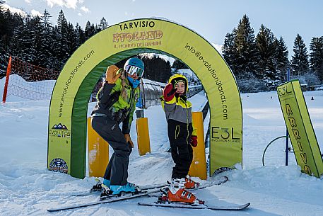 Teacher young woman and child learning alpine skiing in a school camp in Tarvisio.